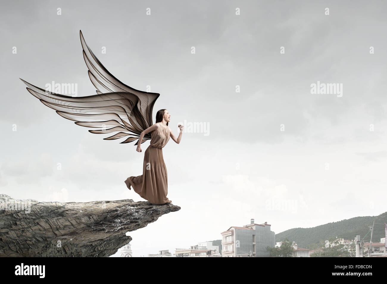 Attractive woman running with angel wings behind back Stock Photo - Alamy