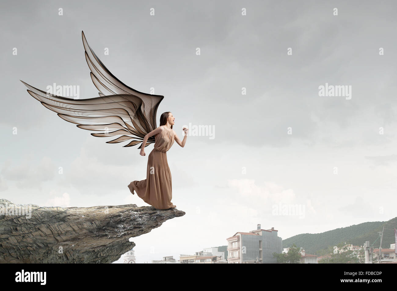 Attractive woman running with angel wings behind back Stock Photo - Alamy