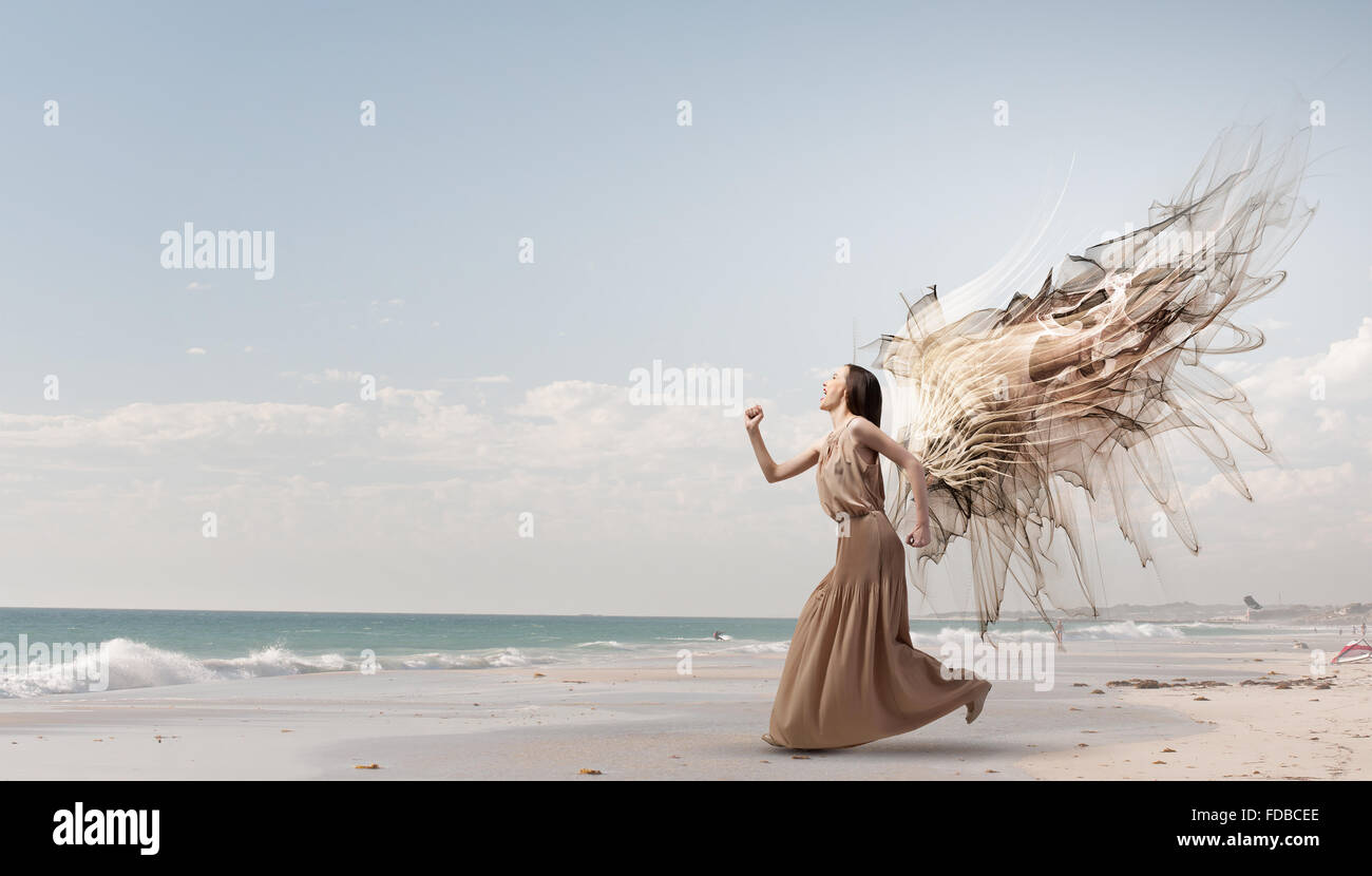 Attractive woman running with angel wings behind back Stock Photo - Alamy