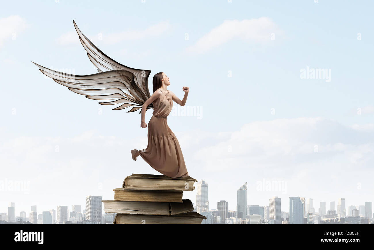 Attractive woman running with angel wings behind back Stock Photo - Alamy