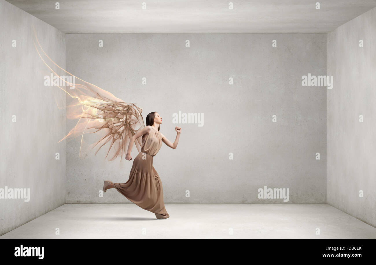 Attractive woman running with angel wings behind back Stock Photo - Alamy