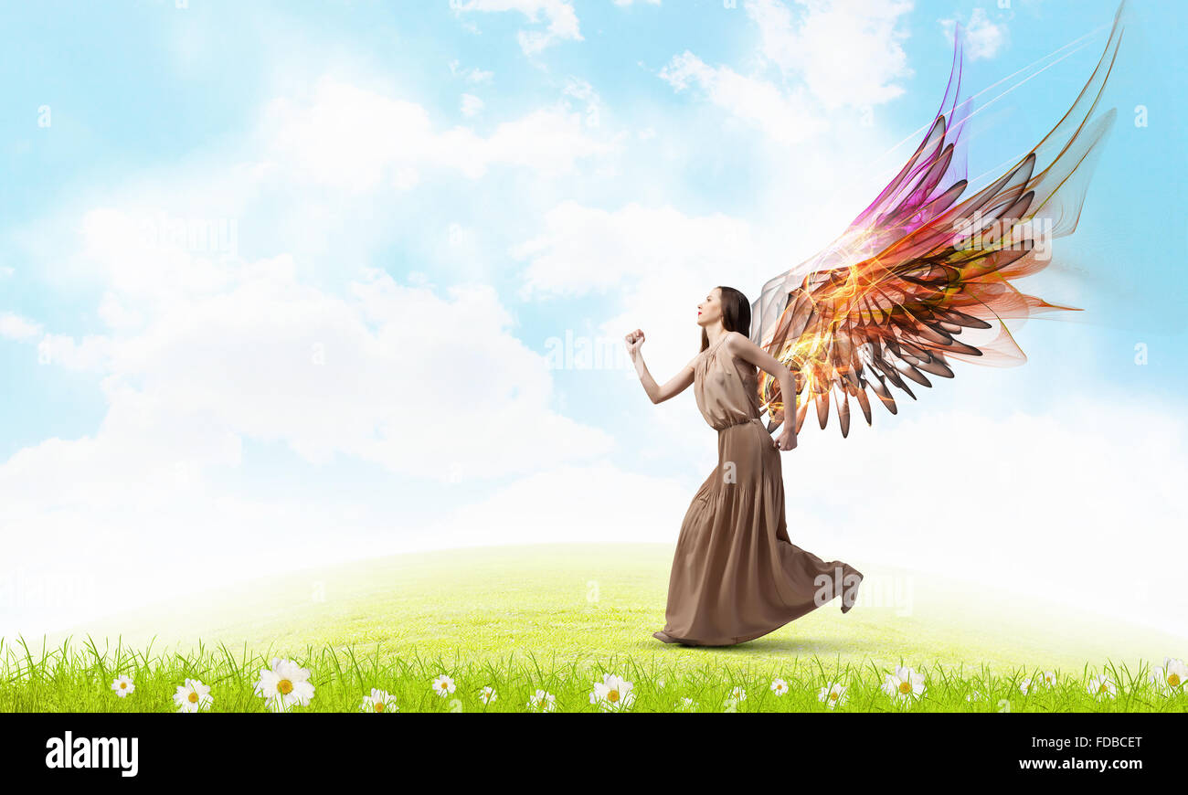 Attractive woman running with angel wings behind back Stock Photo - Alamy