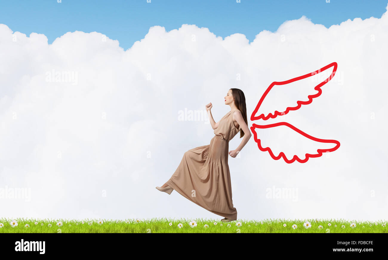 Attractive woman running with angel wings behind back Stock Photo - Alamy