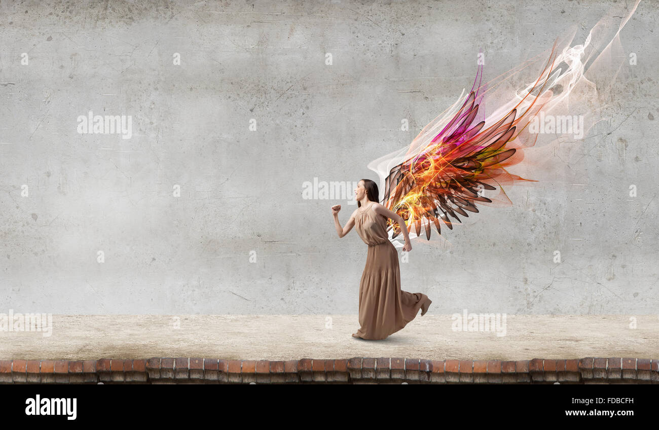 Attractive woman running with angel wings behind back Stock Photo - Alamy