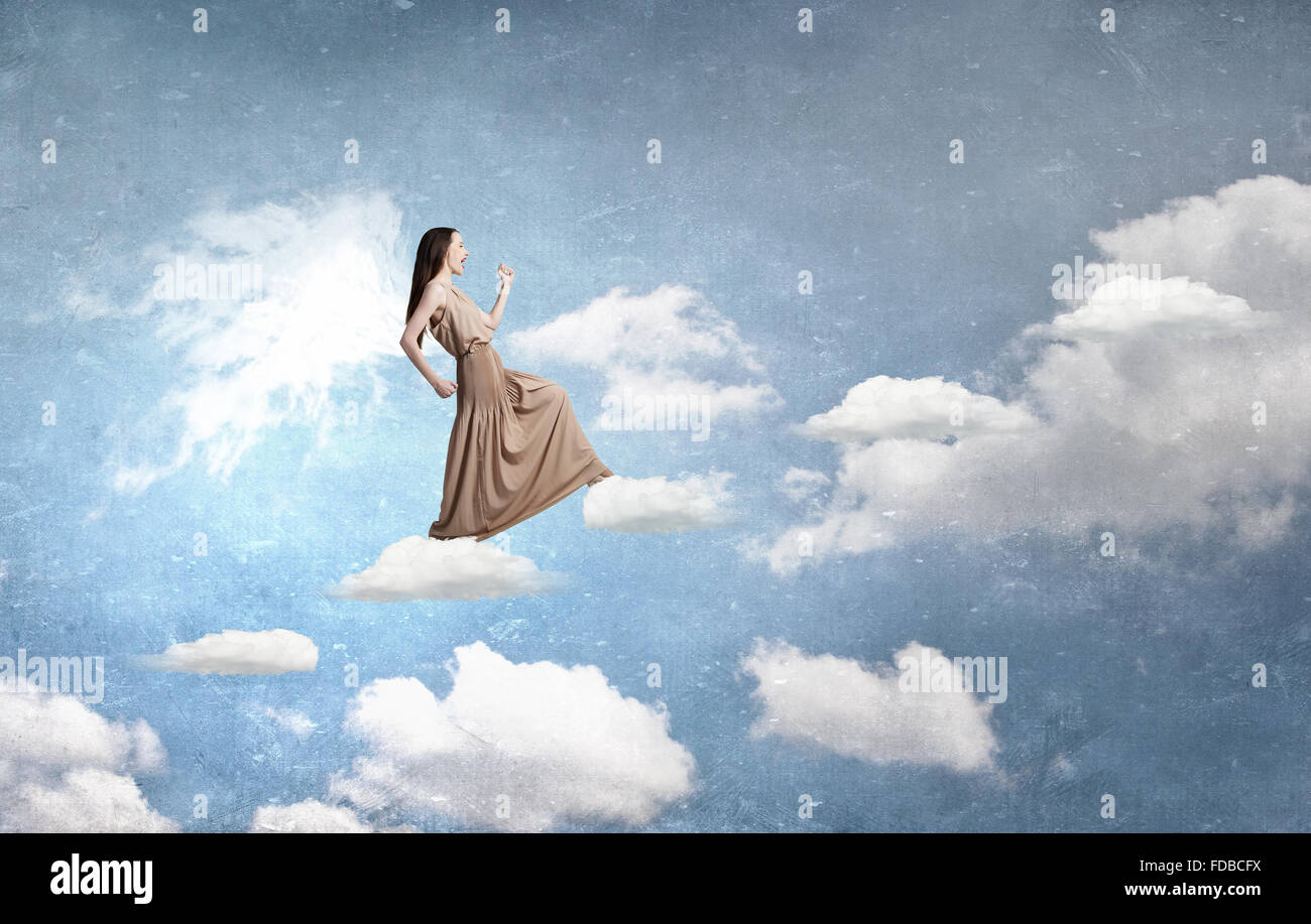 Attractive woman running with angel wings behind back Stock Photo - Alamy