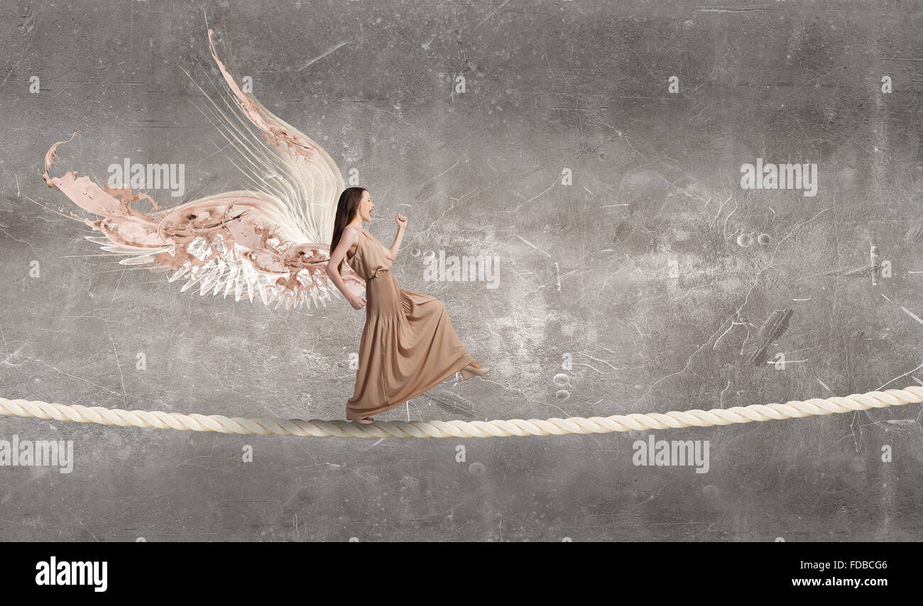 Attractive woman running with angel wings behind back Stock Photo - Alamy