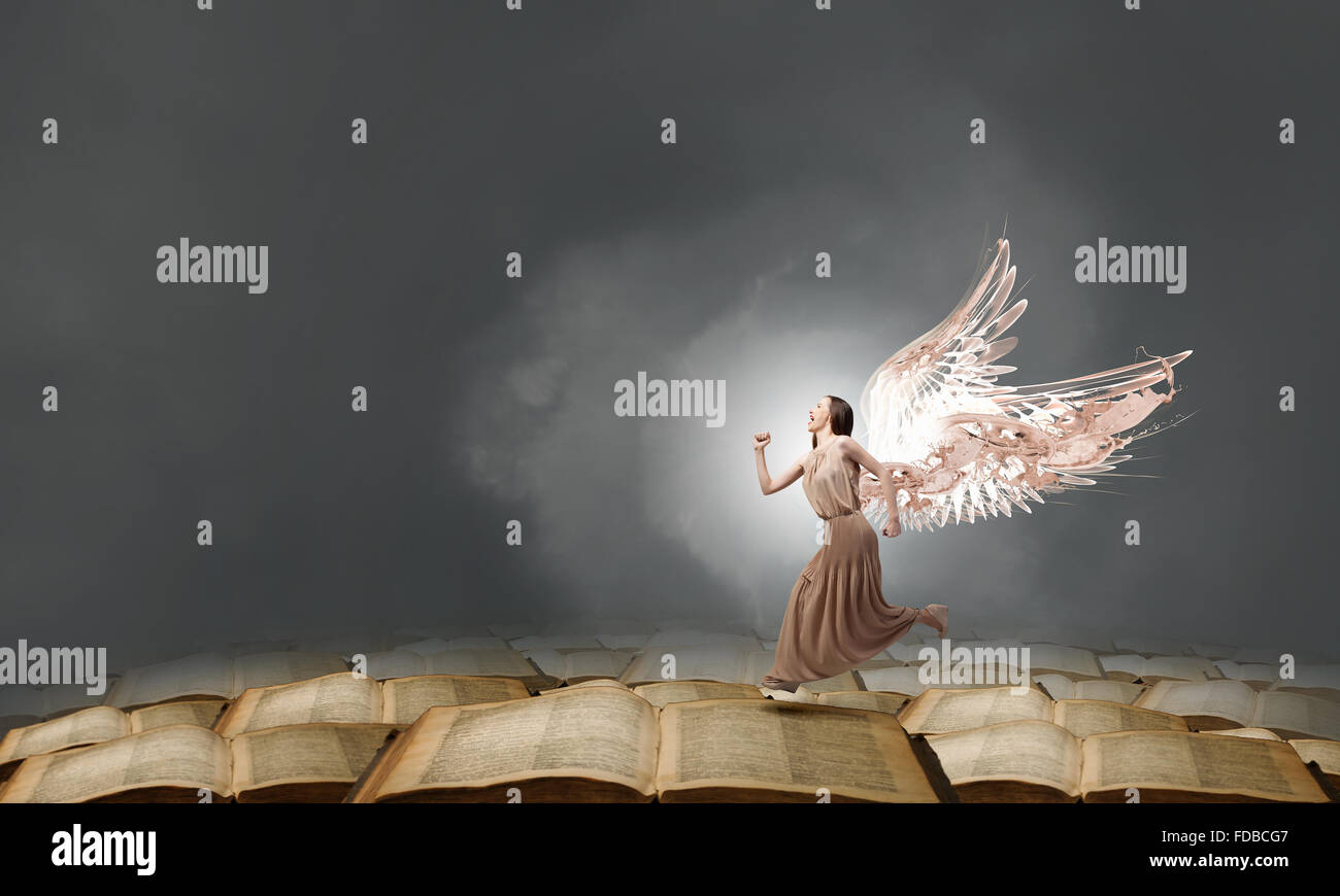 Attractive woman running with angel wings behind back Stock Photo - Alamy