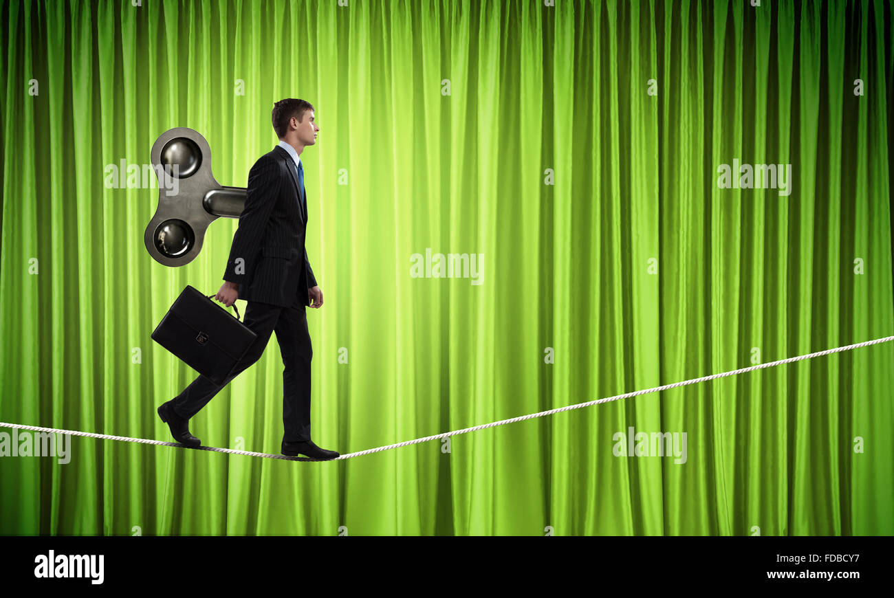 Young businessman walking with wind up key in his back Stock Photo Alamy