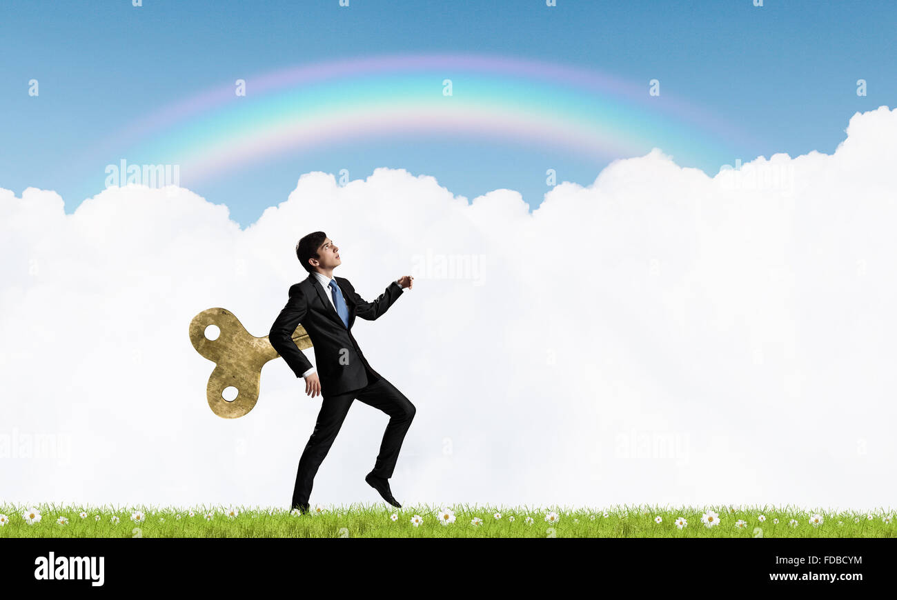 Young businessman walking with wind up key in his back Stock Photo Alamy
