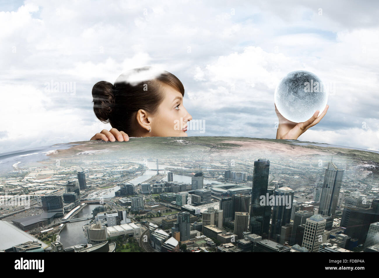 Half of face of businesswoman looking from under table at city model ...