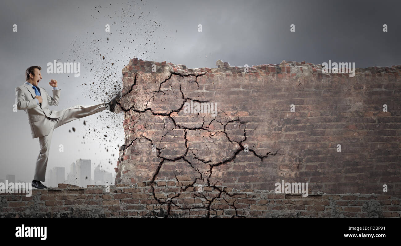 Businessman breaking stone wall with karate kick Stock Photo - Alamy