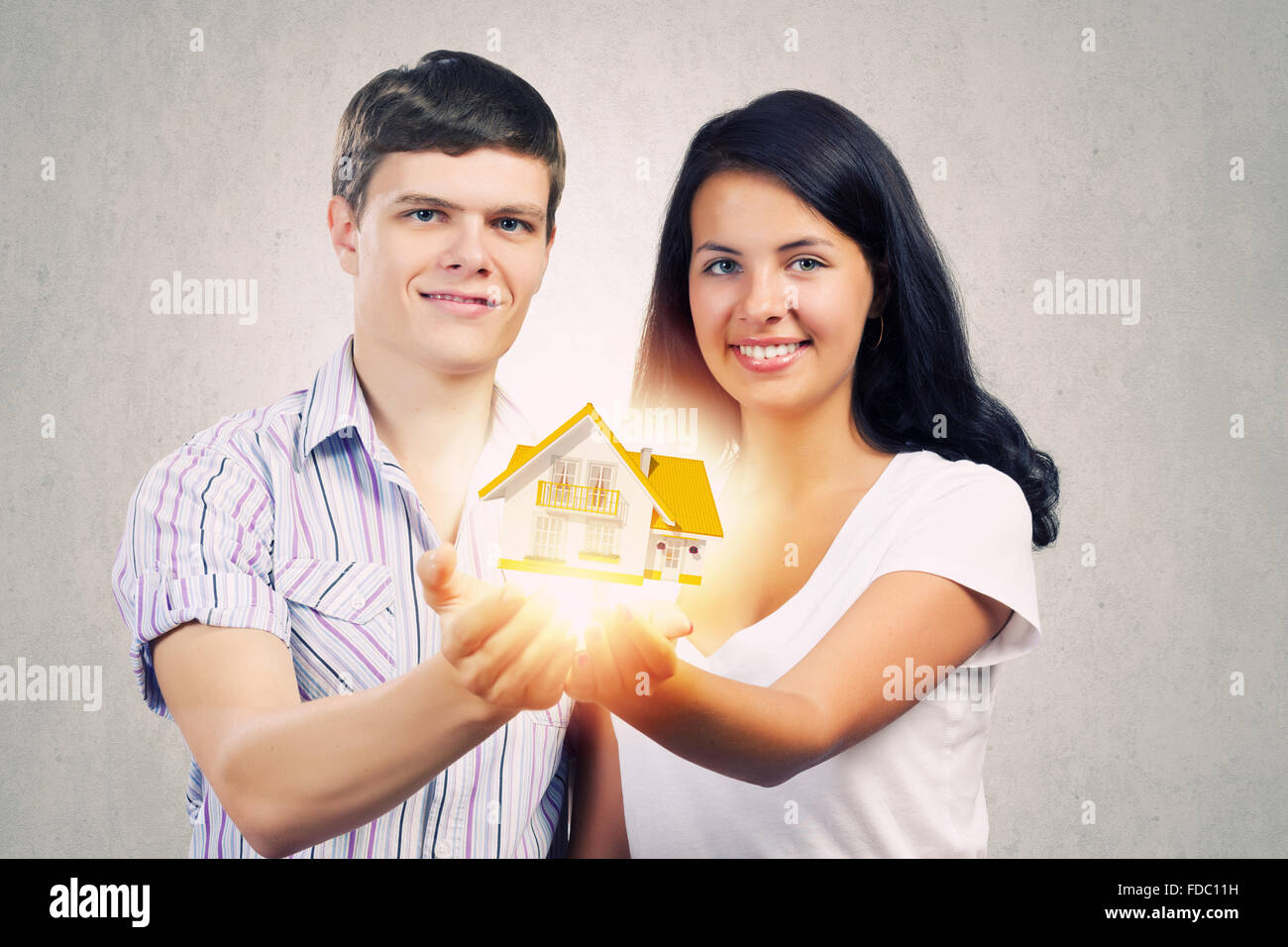 Happy young couple holding model of house on palms Stock Photo - Alamy