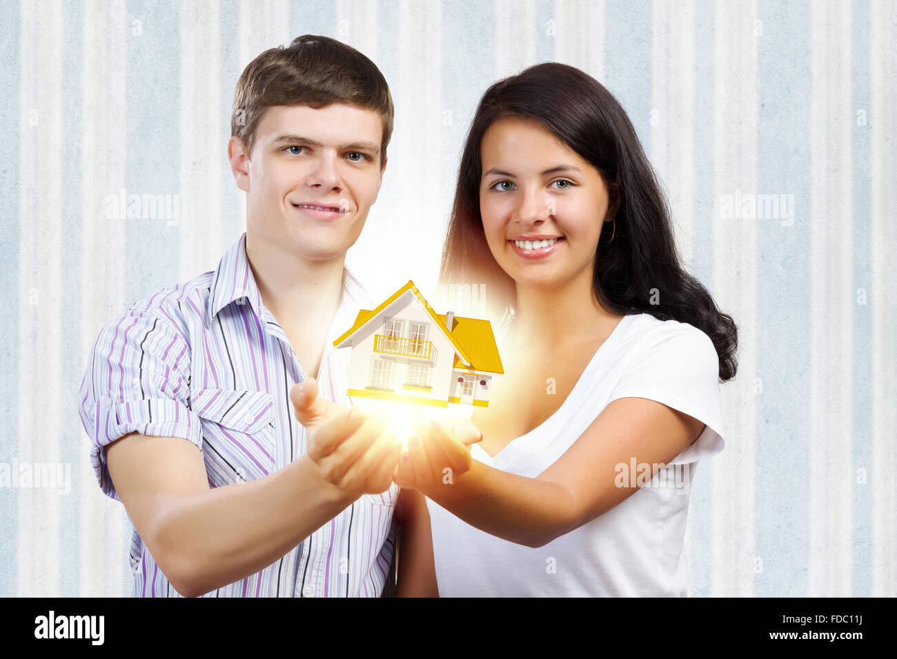 Happy young couple holding model of house on palms Stock Photo - Alamy