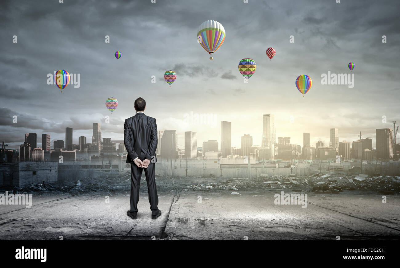 Rear view of businessman looking at aerostats flying above city Stock ...