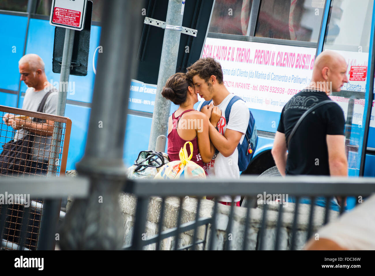 Young couple takes an affectionate farewell snuggling at the bus stop in Marina di Camerota,Campania,Italy Stock Photo