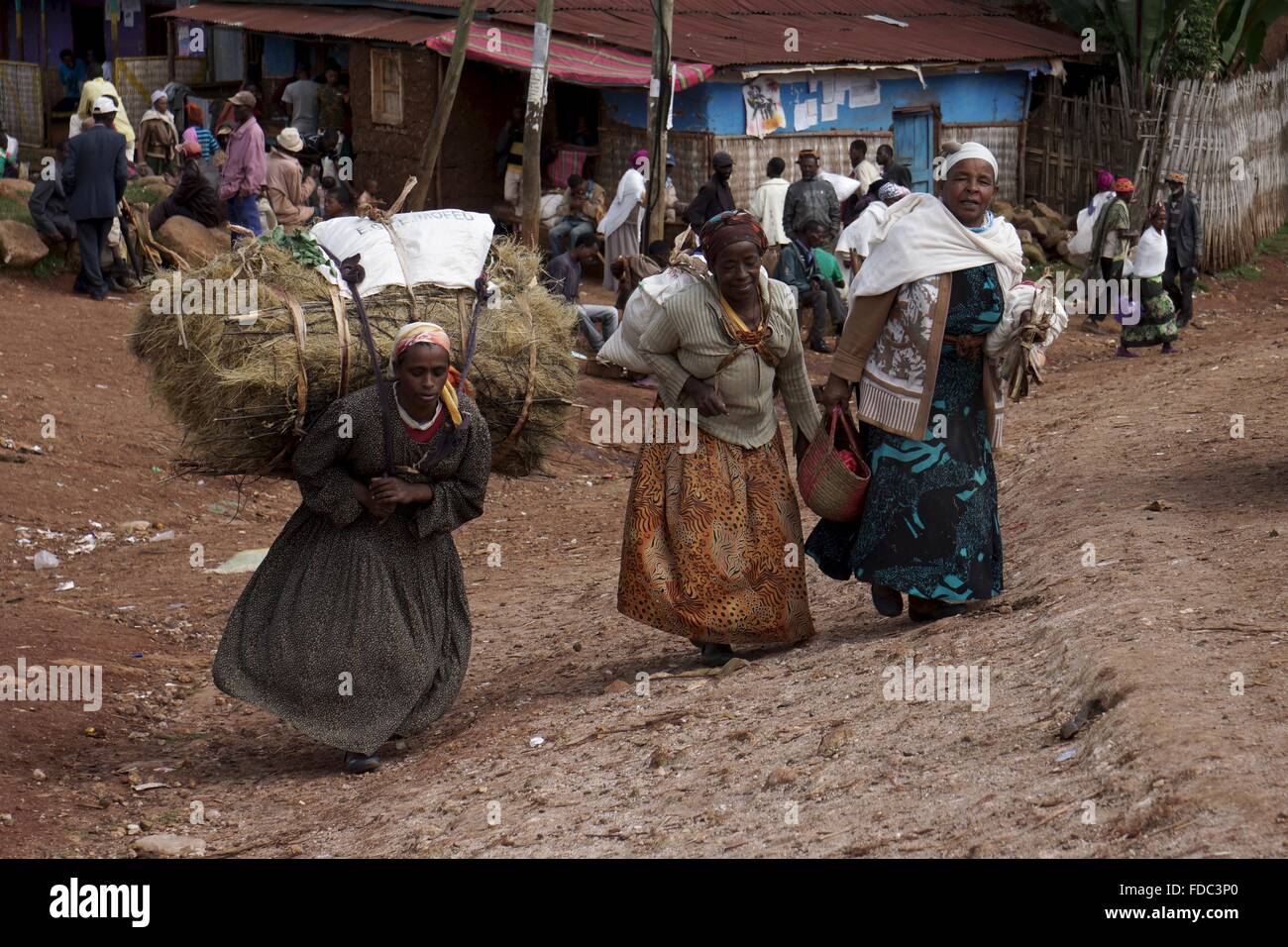 Three ladies carry their produce at the end of a market in a small village in Ethiopia. Stock Photo