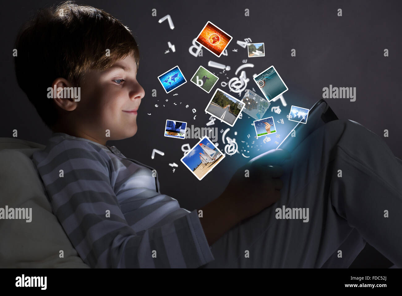 Cute little boy sitting in bed and using tablet pc Stock Photo - Alamy