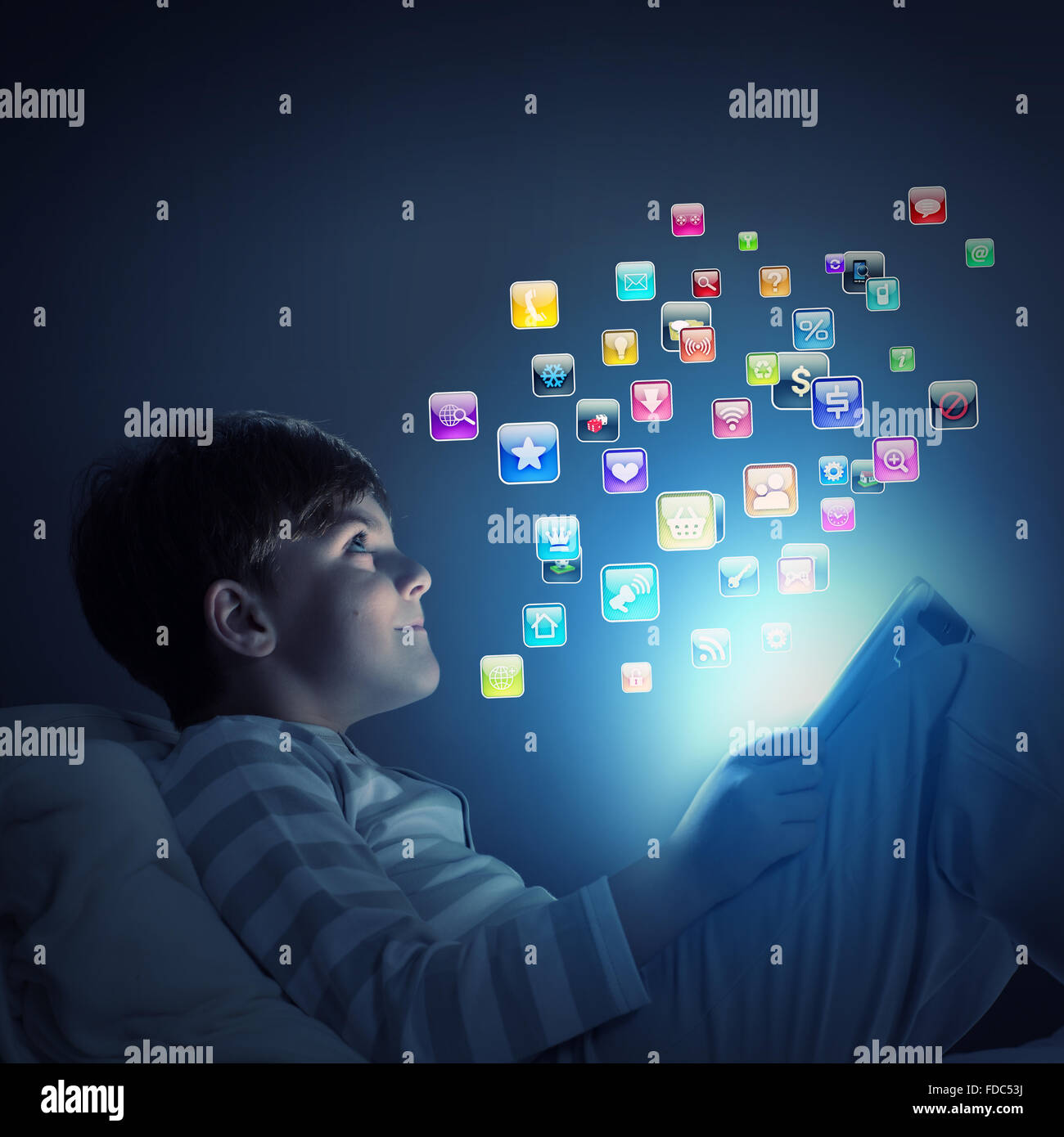 Cute little boy sitting in bed and using tablet pc Stock Photo - Alamy