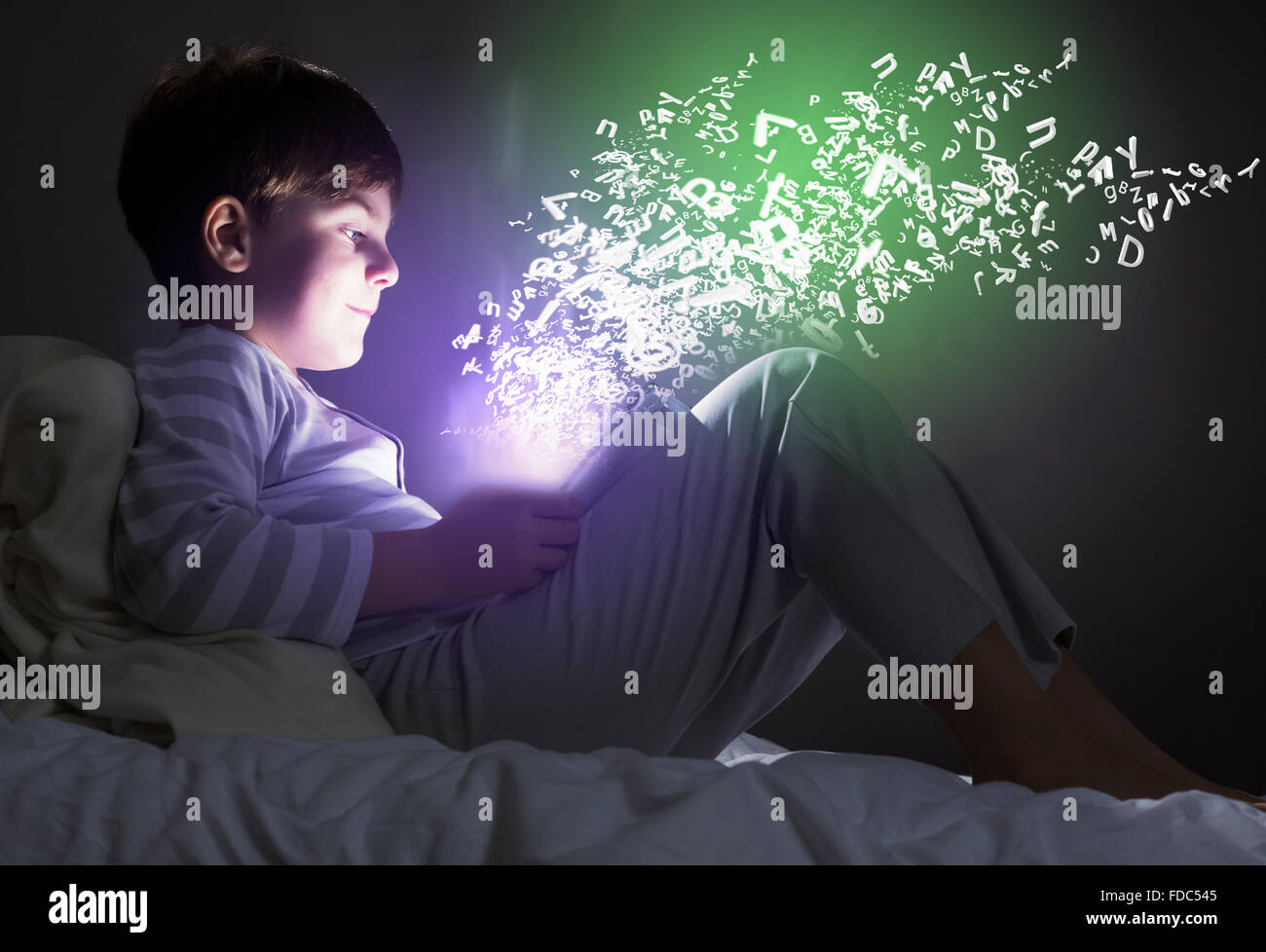 Cute little boy sitting in bed and using tablet pc Stock Photo - Alamy