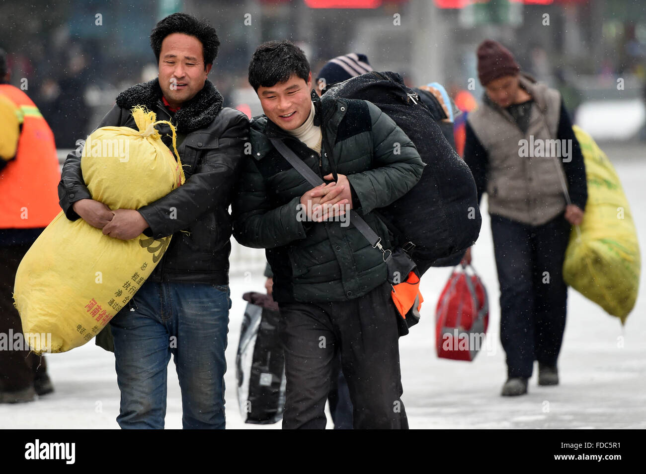 Zhengzhou, China's Henan Province. 30th Jan, 2016. Passengers walk with their luggage amid snow at the railway station of Zhengzhou, capital of central China's Henan Province, Jan. 30, 2016. This year's 'Chunyun', the hectic travel period surrounding Chinese Lunar New Year, or Spring Festival, began on Jan. 24. © Li Bo/Xinhua/Alamy Live News Stock Photo