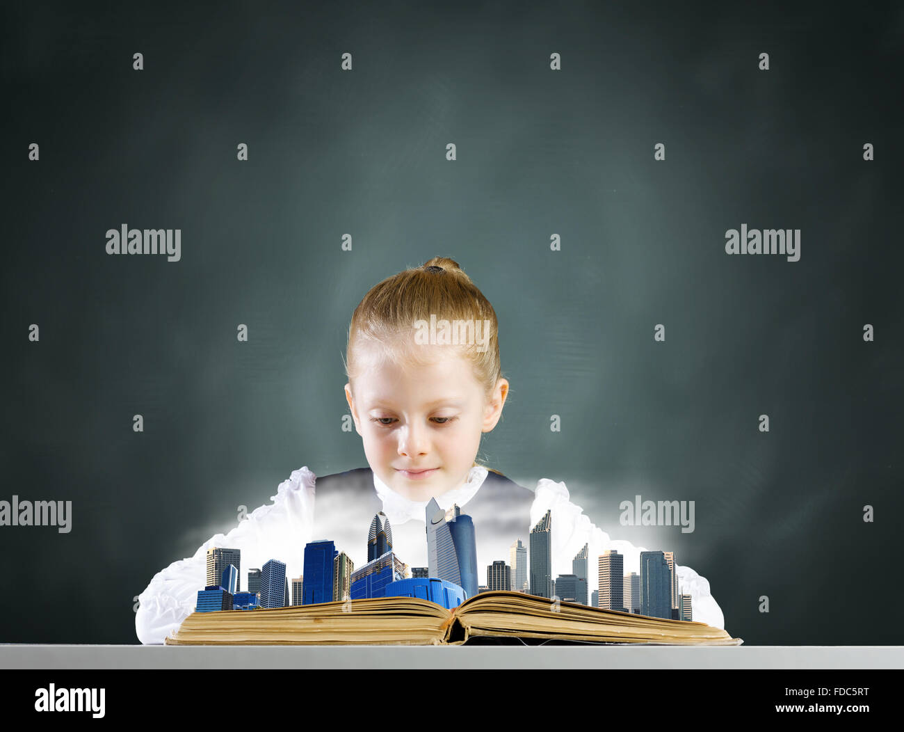 Cute school girl looking in opened book with city model Stock Photo - Alamy