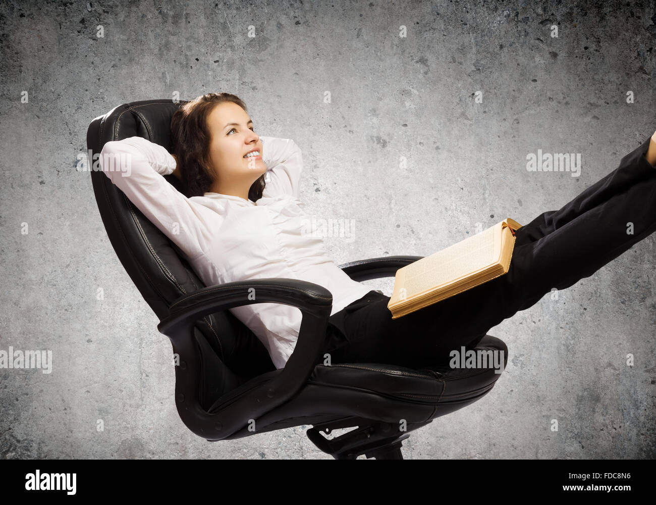 Young businesswoman sitting in chair and reading book Stock Photo - Alamy