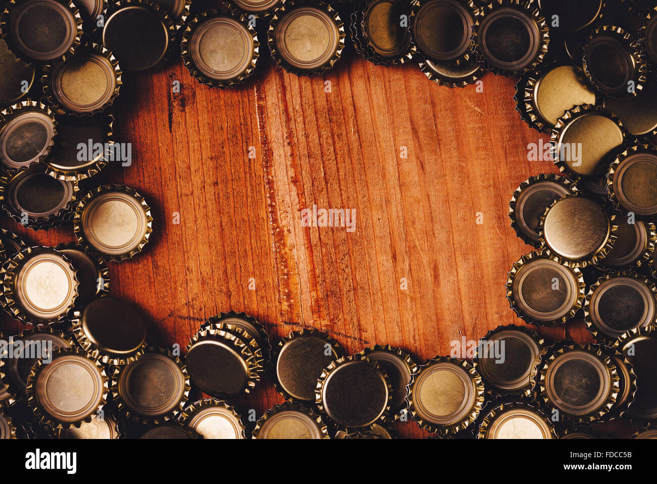 Beer bottle caps forming frame over oak wood plank as copy space Stock
