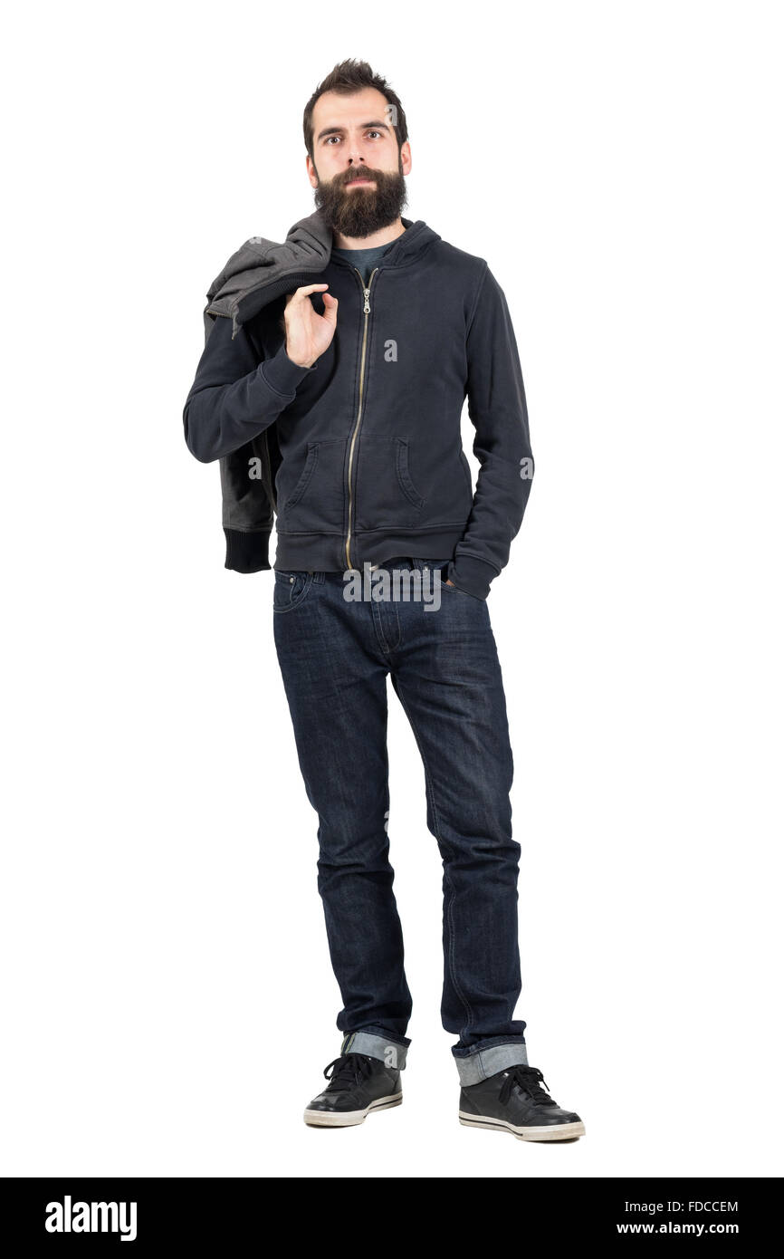 Serious hipster in hooded sweatshirt carrying jacket over the shoulder looking at camera. Full body length portrait isolated Stock Photo