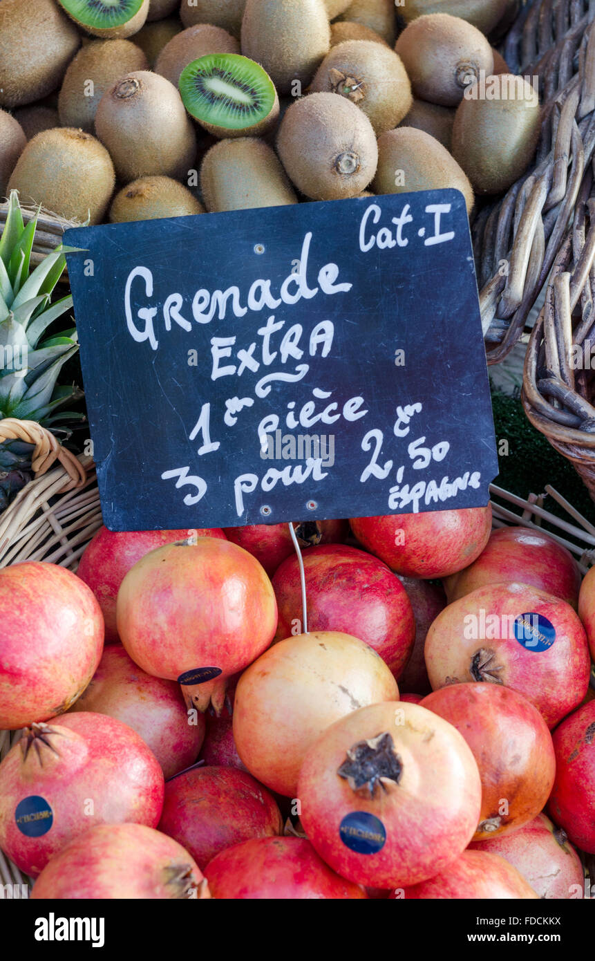 Pomegranate/ grenade fruits and kiwi fruits for sale on a French farmers market stall, displayed in wicker baskets with pricetag Stock Photo