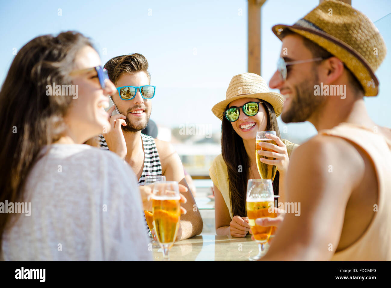 Friends having fun and drinking a cold beer at the beach bar Stock Photo