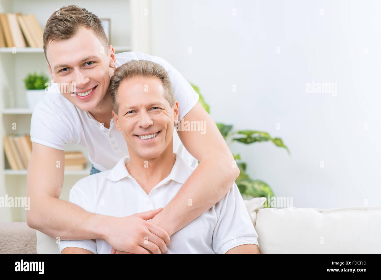 Father and adult son sitting on the sofa Stock Photo