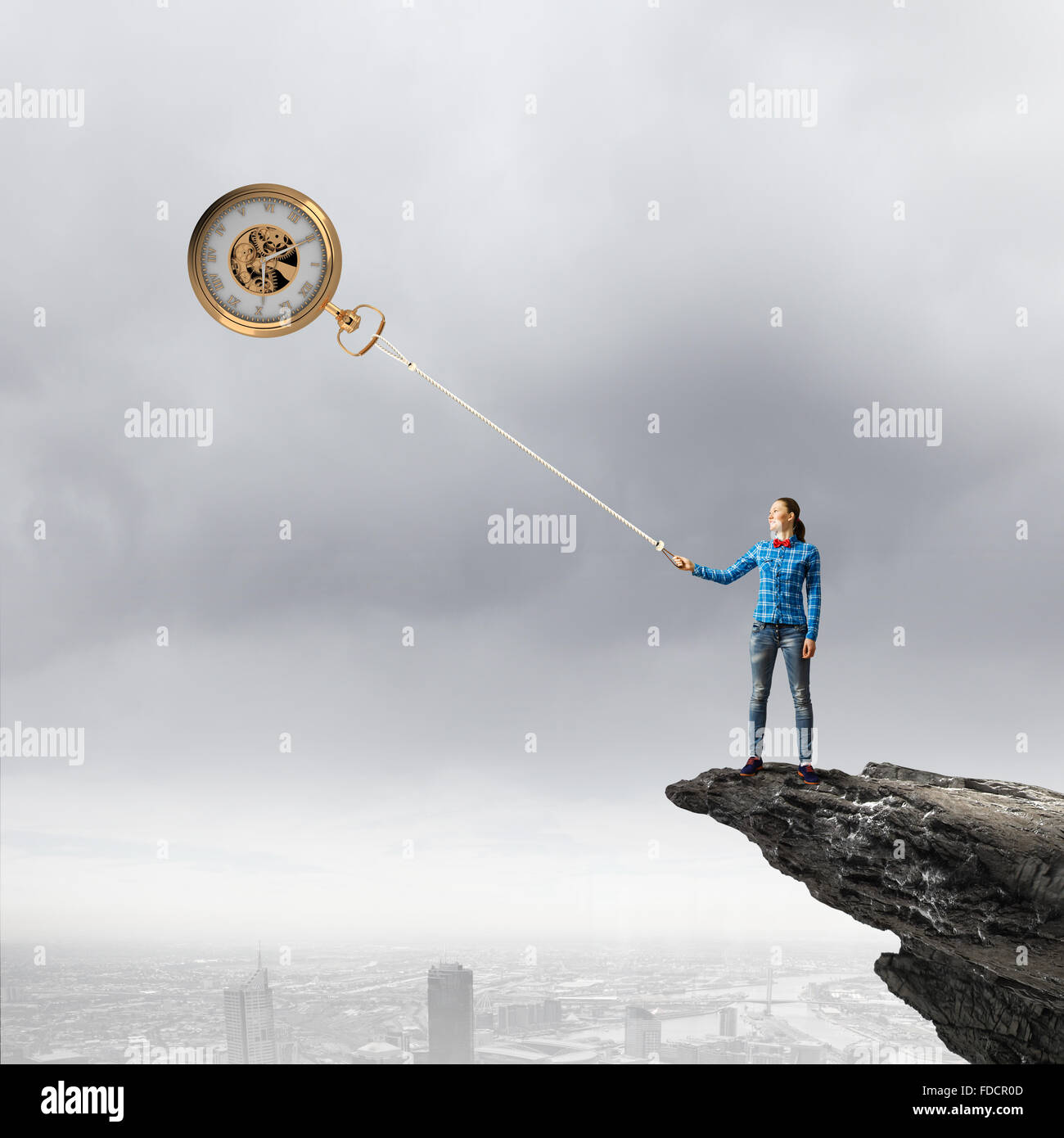 Young woman in casual catching clock with rope Stock Photo - Alamy
