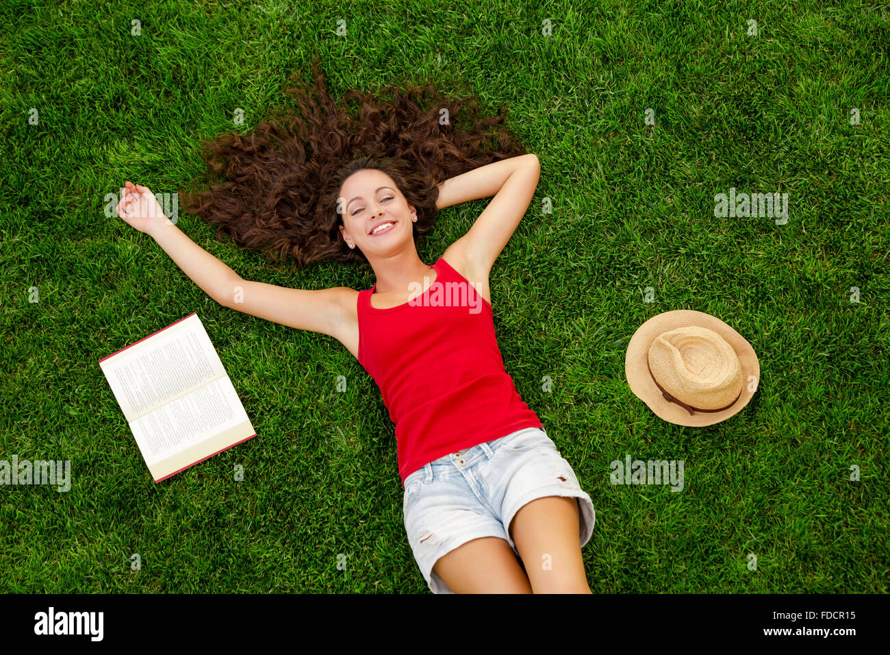 Beautiful and happy young woman lying on the grass Stock Photo - Alamy