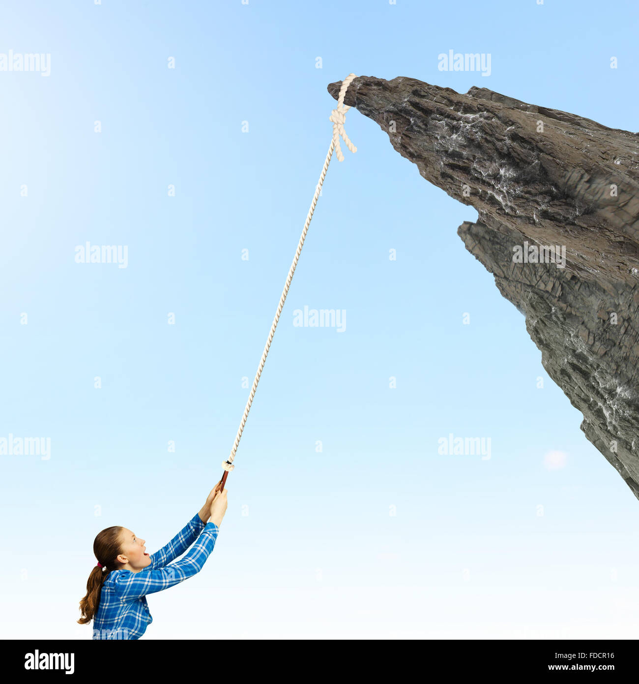 Young woman climbing rock with help of rope Stock Photo - Alamy