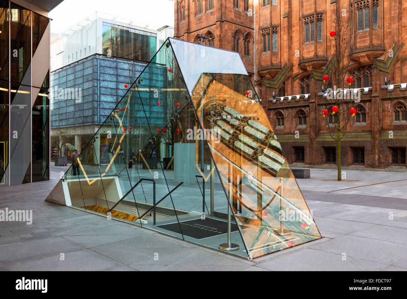 The glass entrance to the underground Australasia Restaurant, Spinningfields, Deansgate, Manchester, UK. John Rylands library behind. Stock Photo