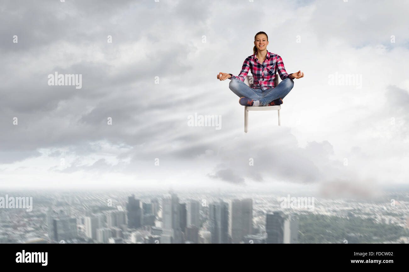 Young woman sitting on chair and meditating Stock Photo - Alamy