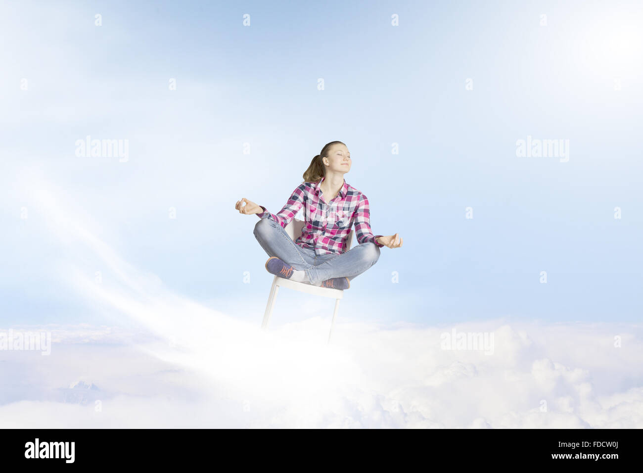 Young woman sitting on chair and meditating Stock Photo - Alamy