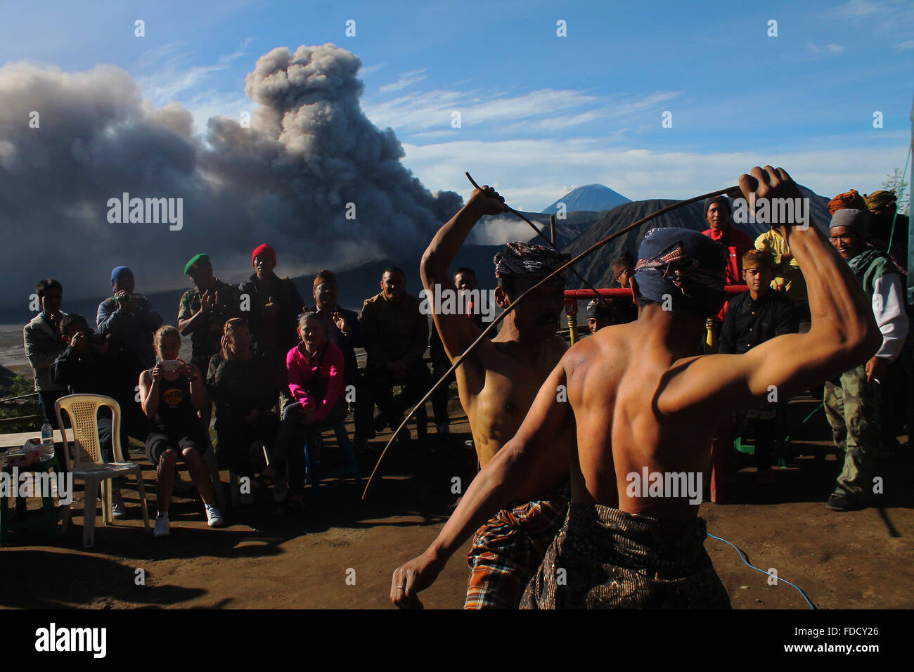 Probolinggo, East Java, Indonesia. 30th Jan, 2016. Tenggerese performs a traditional dance called 'Ujung-Ujungan' while Mount Bromo erupts in background. The ritual is one of the traditional dances by two men who alternated hitting the opponent by using rattan Palm branch. Credit:  Suryanto/ZUMA Wire/Alamy Live News Stock Photo