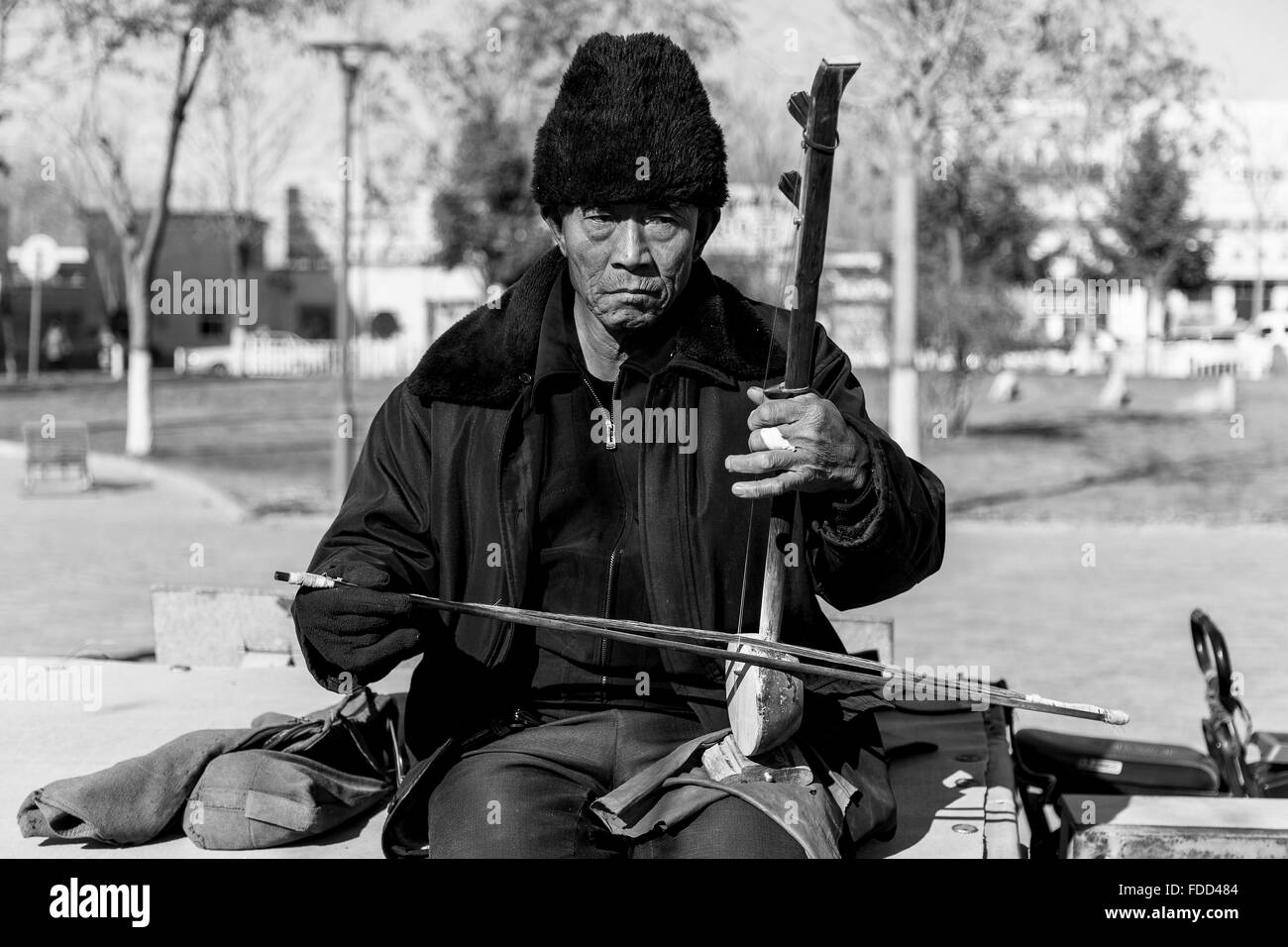 Zhongwei, China - January 2016. Street Musician playing the Erhu on a cold afternoon. Stock Photo
