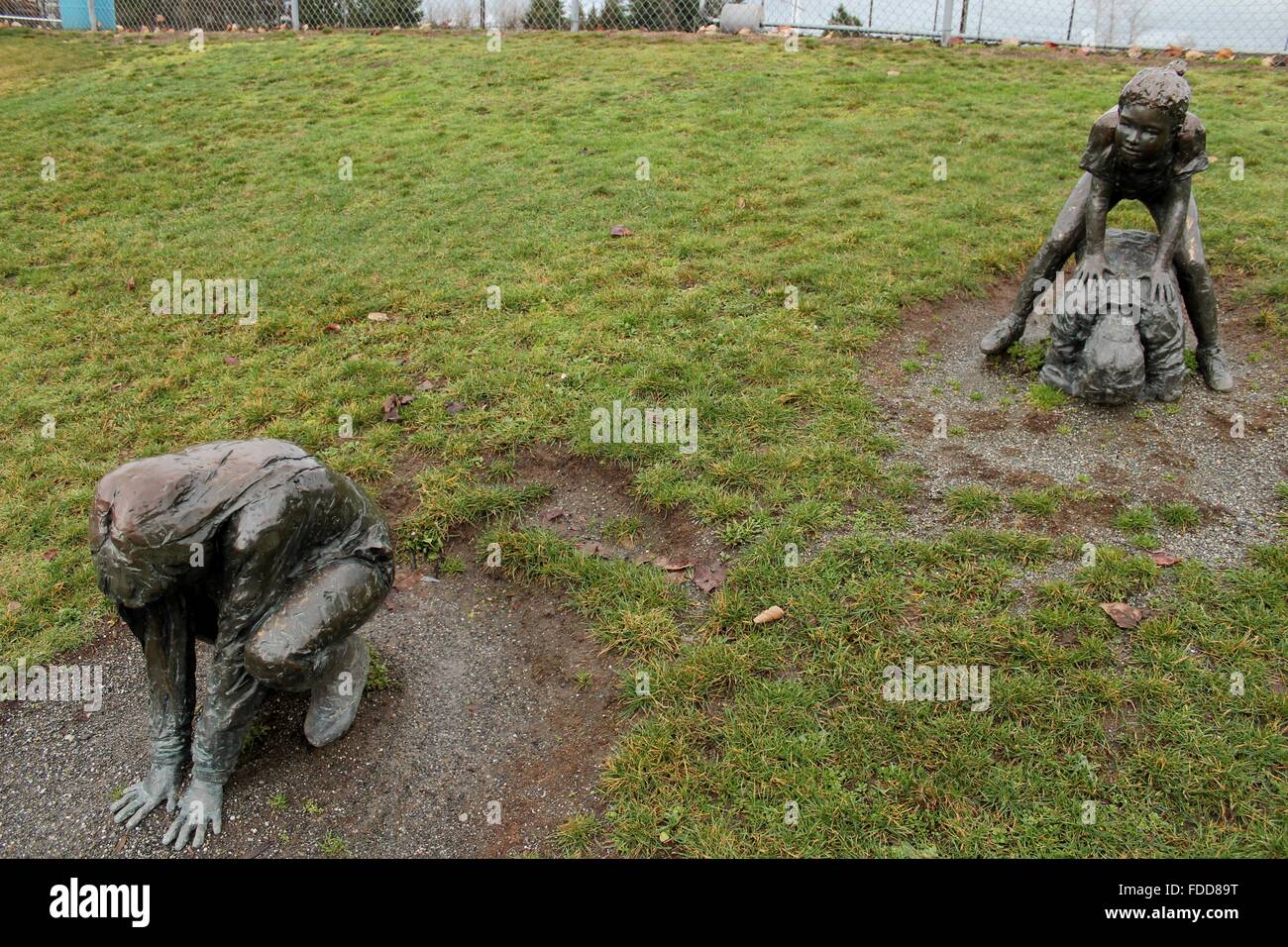 Pair of bronze statues of children playing in a park. Stock Photo