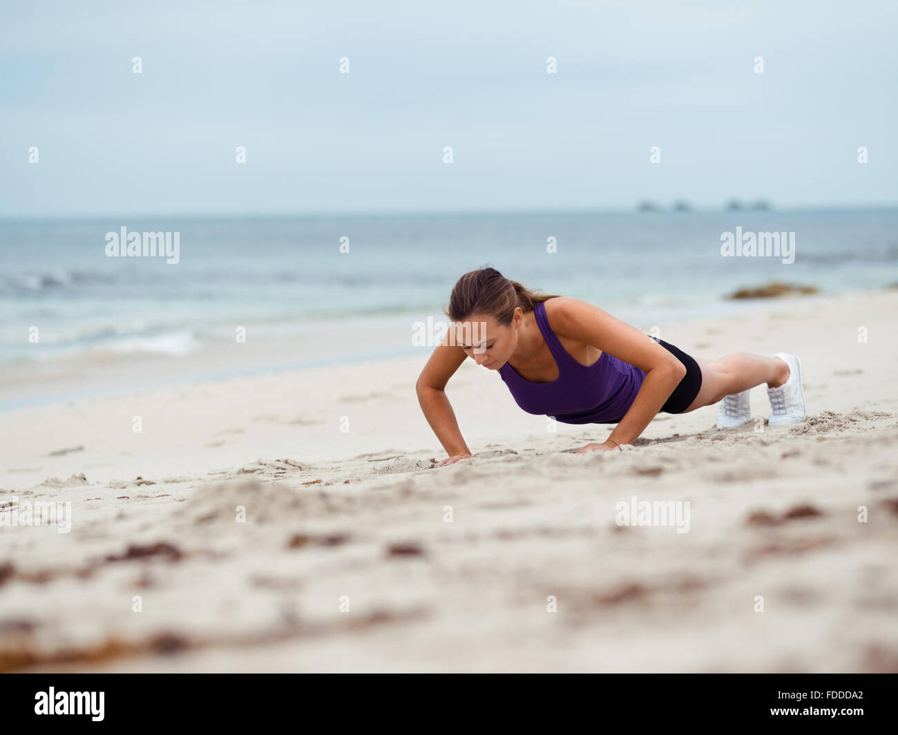 Sporty young woman doing push ups on the sea coast Stock Photo - Alamy