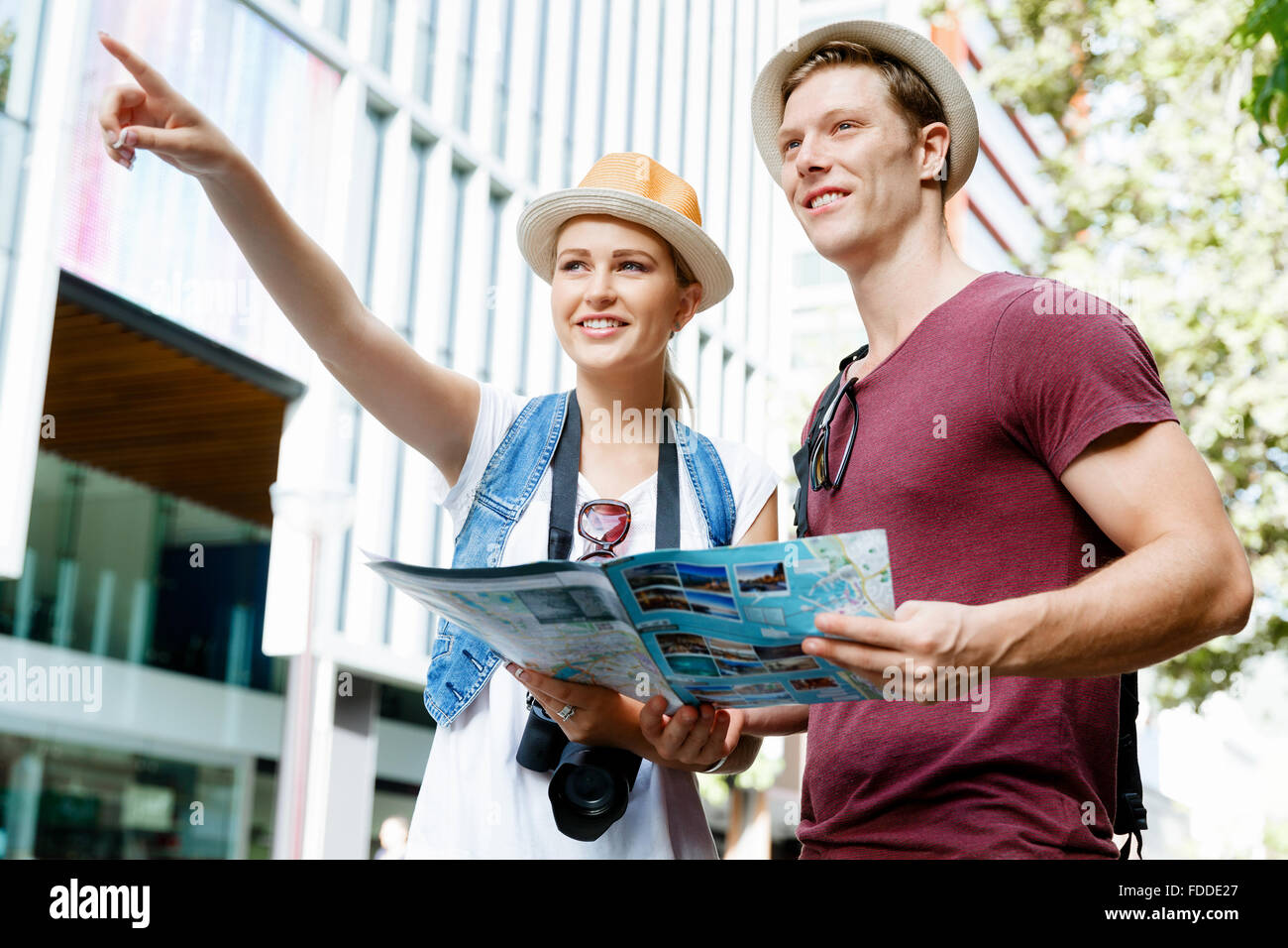 Happy young couple as tourists with a map Stock Photo - Alamy