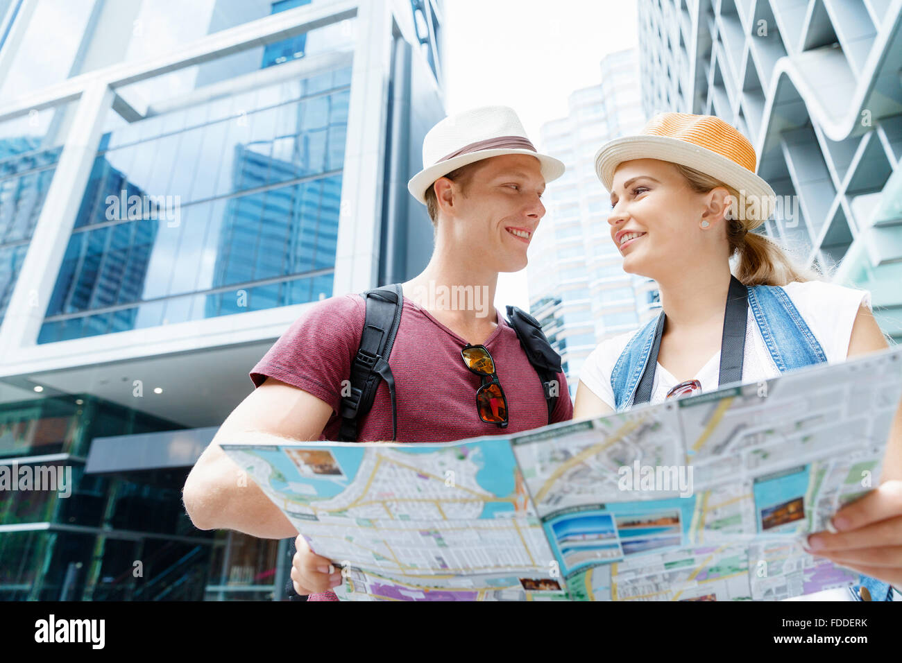 Happy young couple as tourists with a map Stock Photo - Alamy