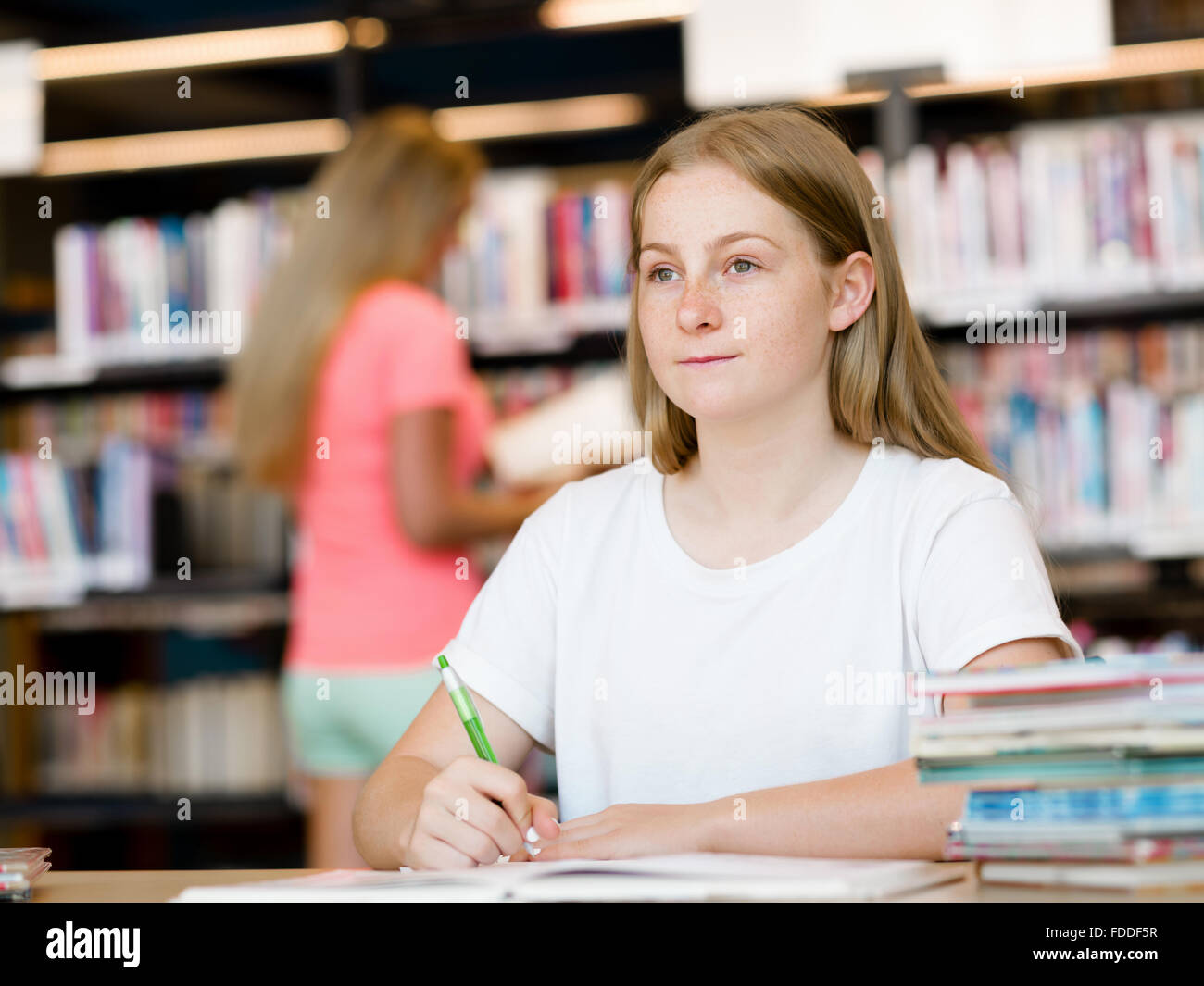 Teenage girl with books studying in library Stock Photo - Alamy
