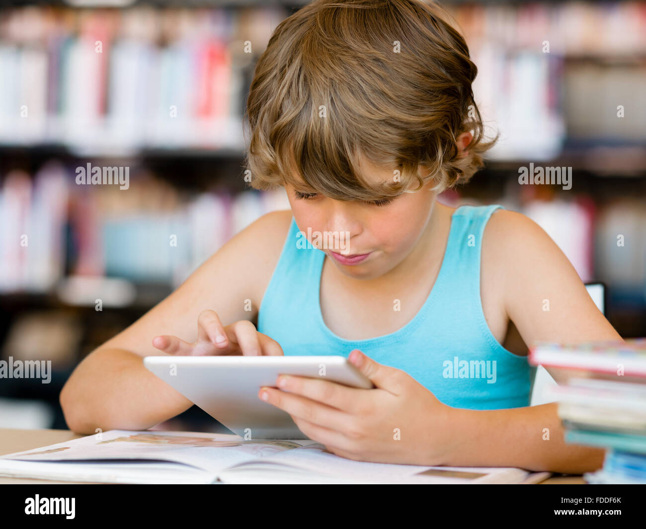 Little boy sitting with tablet in library Stock Photo - Alamy