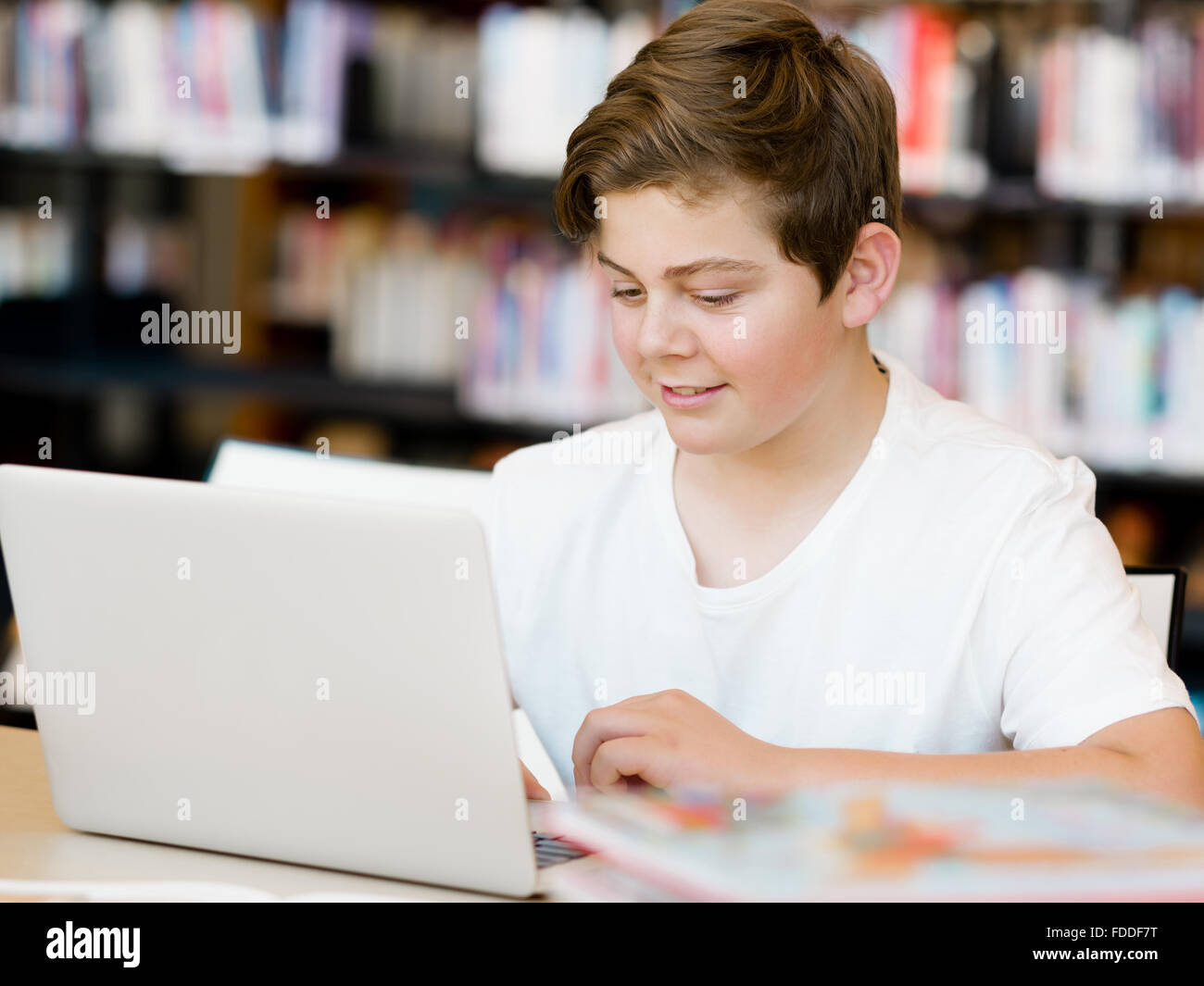 Teenage boy sitting with tablet in library Stock Photo - Alamy