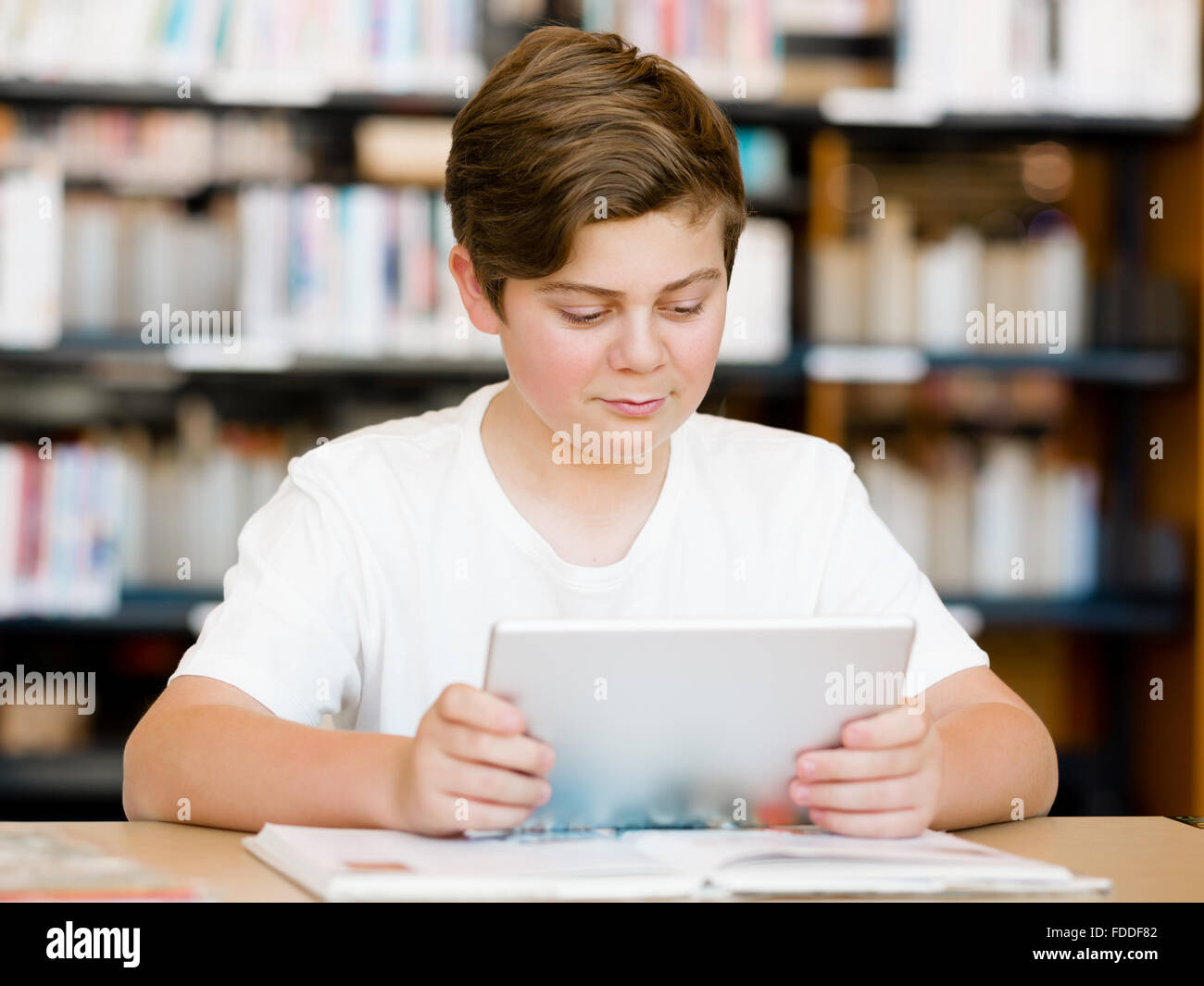 Teenage boy sitting with tablet in library Stock Photo - Alamy