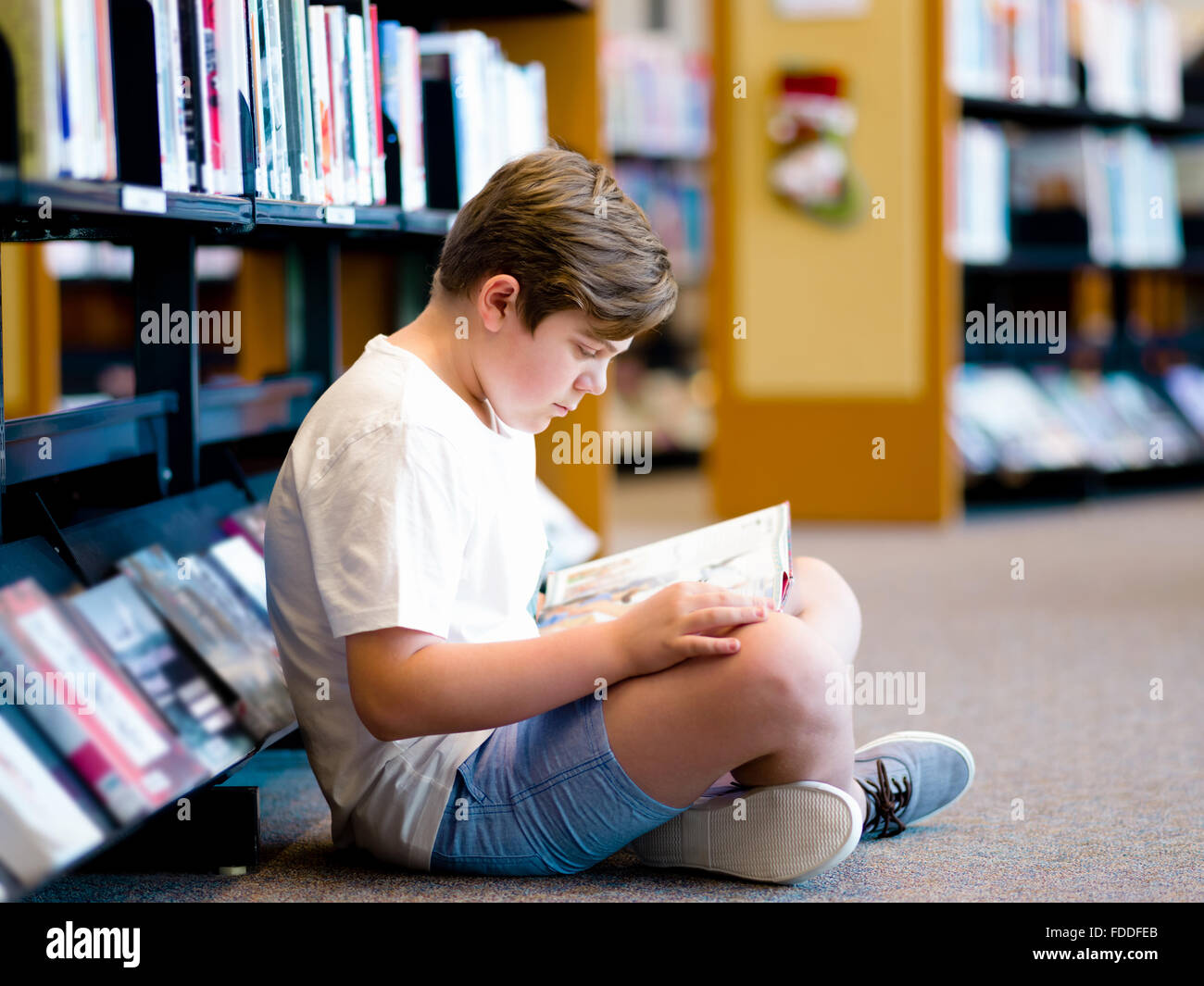 Boy in library with books Stock Photo - Alamy