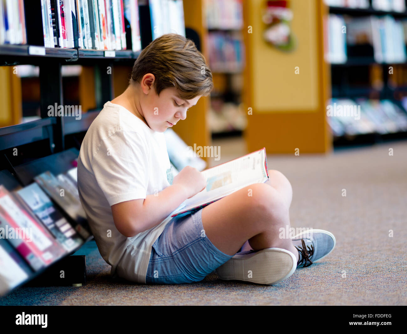 Boy in library with books Stock Photo - Alamy