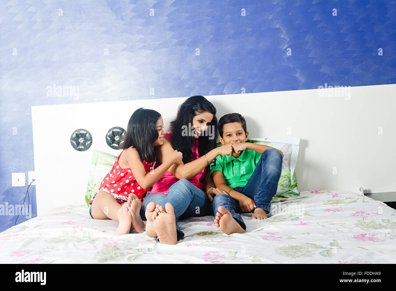 3 people mother and kids daughter and son sitting Bedroom Fun Stock Photo